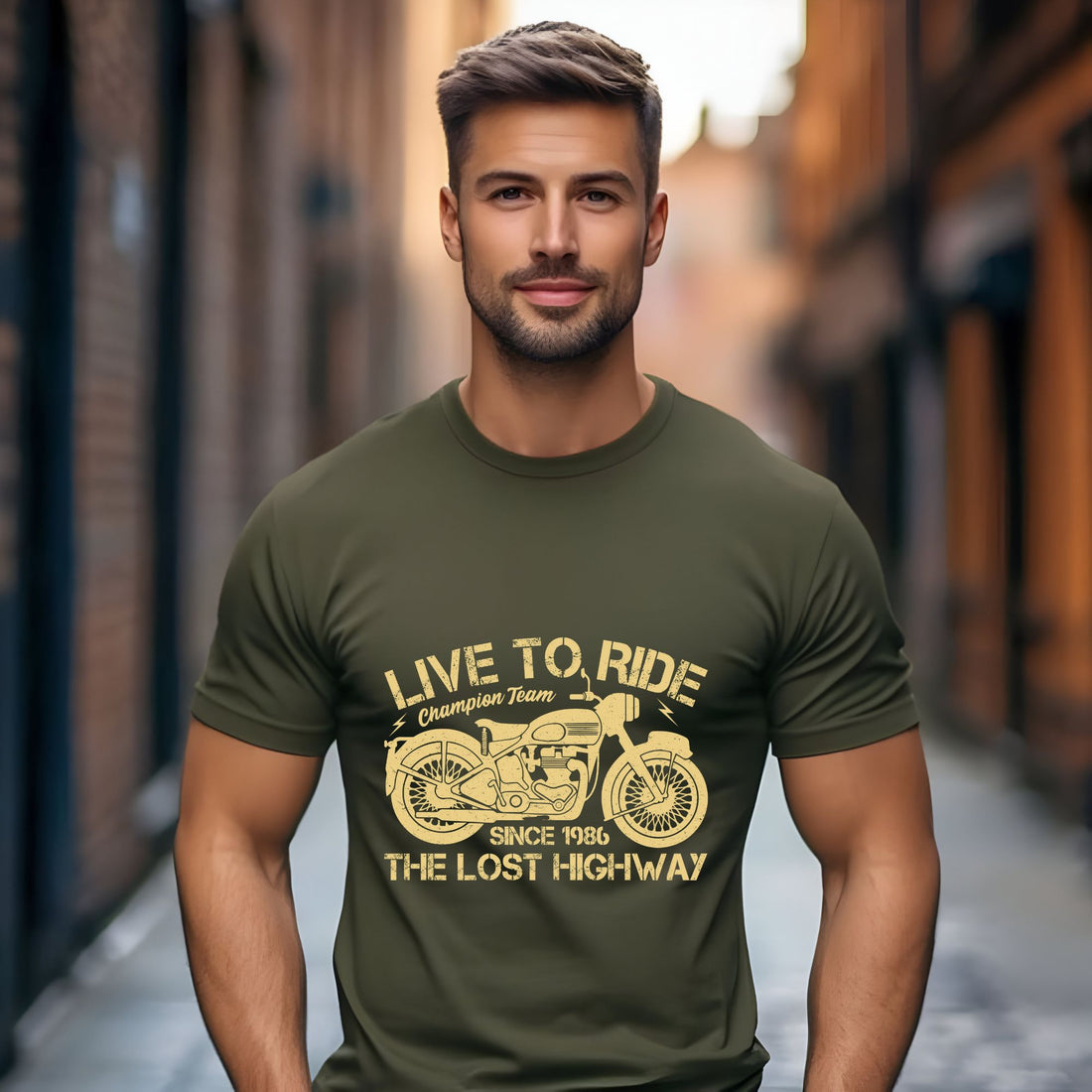 Man wearing an olive green “Live to Ride” motorcycle t-shirt with a vintage motorbike print, standing in an urban setting.