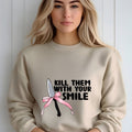 Bold beige sweatshirt featuring 'Kill Them with Your Smile' graphic with a knife and pink bow. Cozy and edgy design for women.