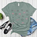 Cute Smiley & Bow Graphic T-Shirt in green, paired with ripped denim shorts and sandals. Trendy aesthetic outfit.
