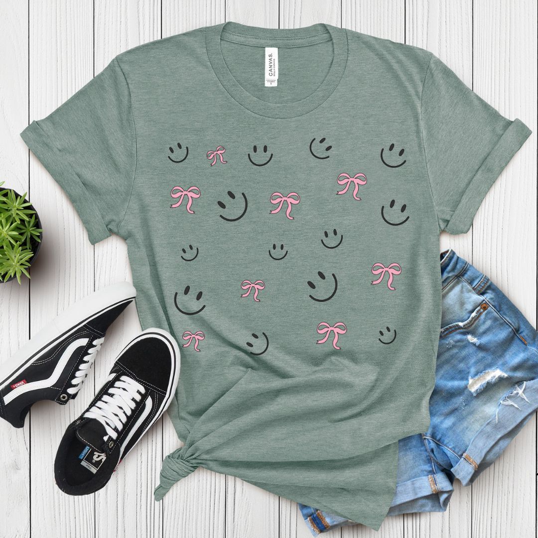 Cute Smiley & Bow Graphic T-Shirt in green, paired with ripped denim shorts and sandals. Trendy aesthetic outfit.