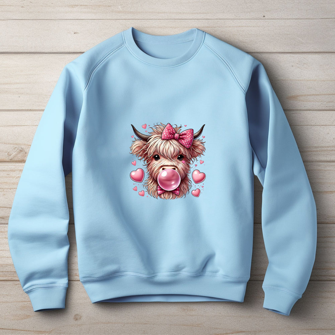 Black sweatshirt with a highland cow graphic wearing a pink bow and blowing bubblegum, surrounded by pink hearts.