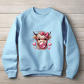 blue sweatshirt with a highland cow graphic wearing a pink bow and blowing bubblegum, surrounded by pink hearts.