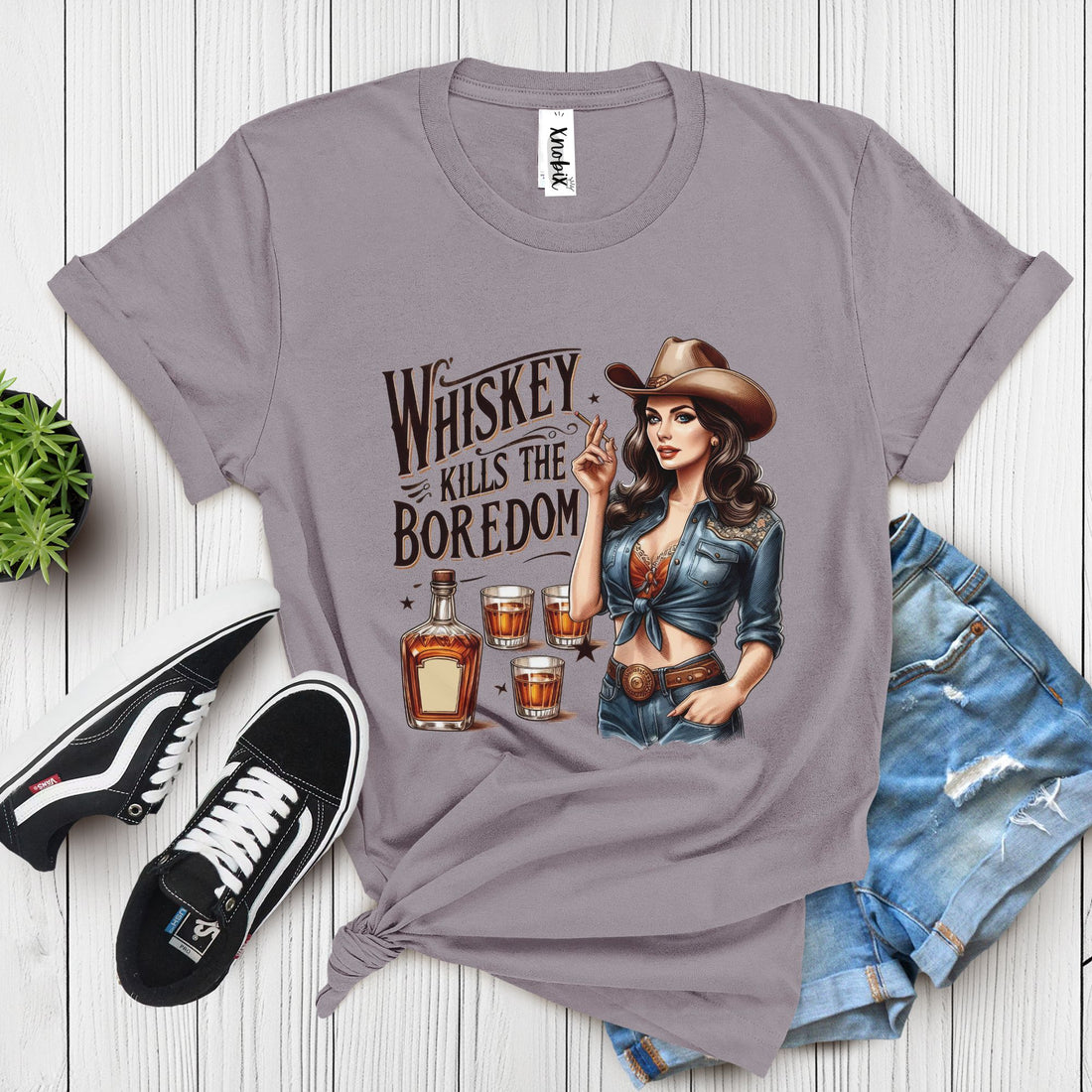 Western-style gray t-shirt with vintage cowgirl, whiskey bottle, and shot glasses illustration – "Whiskey Kills the Boredom" design