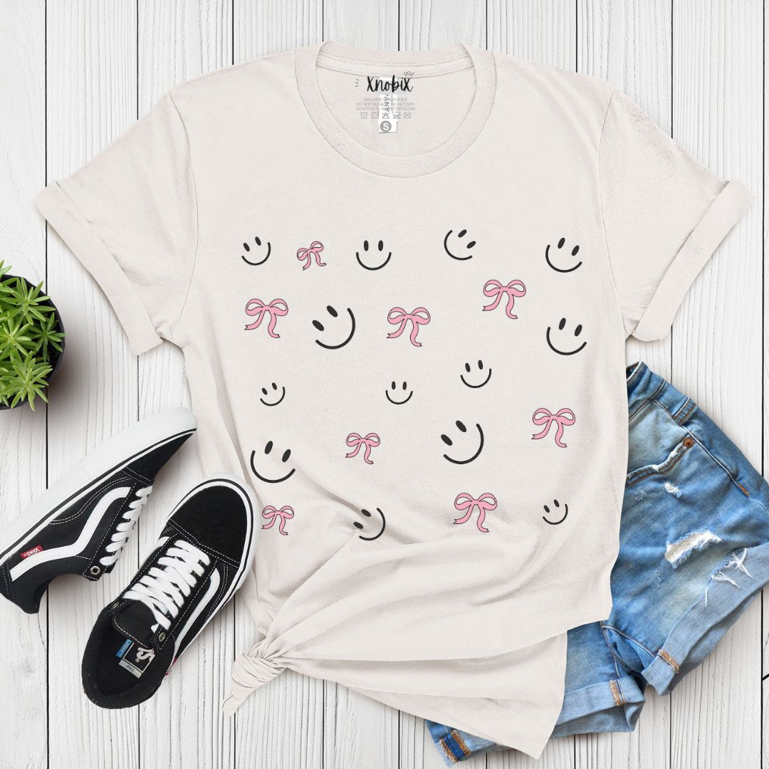 "Cute Smiley & Bow Graphic T-Shirt in gray, paired with ripped denim shorts and sandals. Trendy aesthetic outfit."